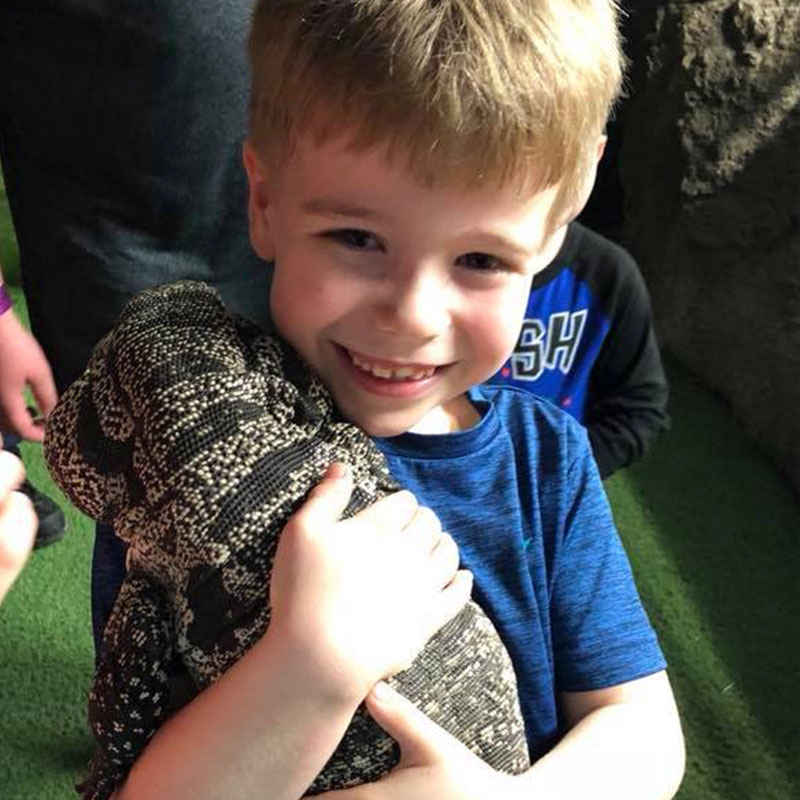 young guest holds a lizard on shoulder